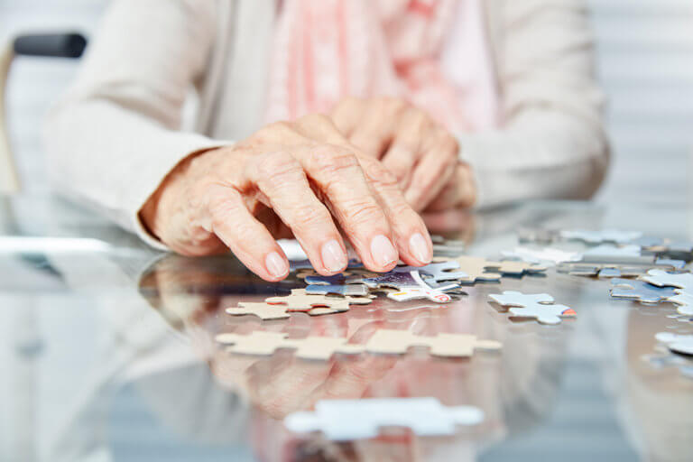 senior woman in memory care program doing puzzle