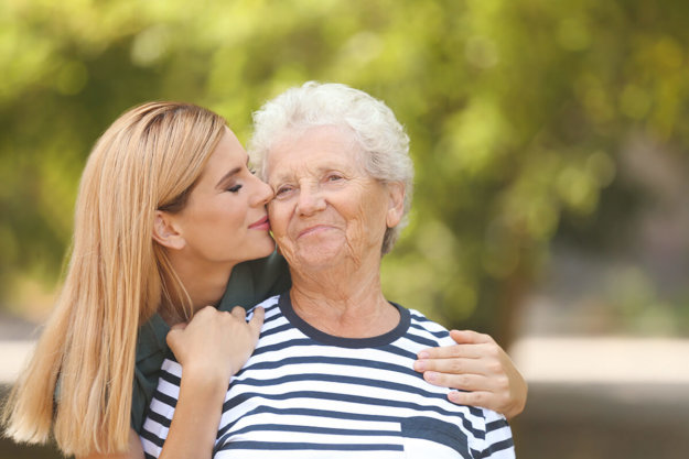 daughter kissing senior mom on cheek knowing she needs assisted living