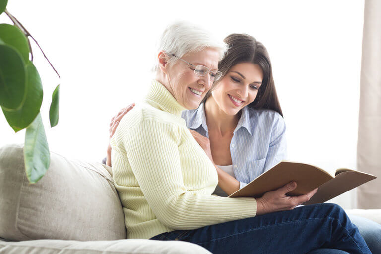 senior woman with daughter reading paper on What Is Memory Care