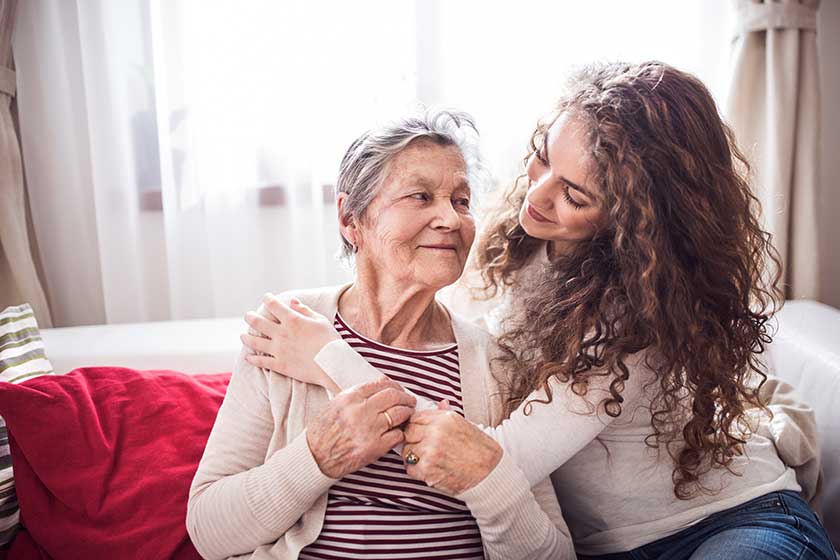 A teenage girl with grandmother at home, hugging.