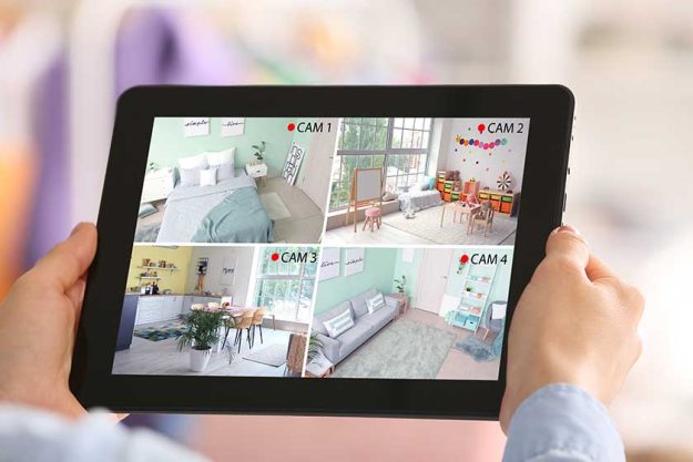 Woman with tablet computer looking at the images of cctv cameras installed in apartment