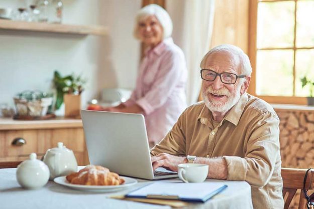 Smiling elderly spouses staying at the kitchen at their home Smiling elderly spouses staying at the kitchen at their home