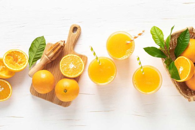 Freshly squeezed juice in glasses and fresh fruits with leaves
