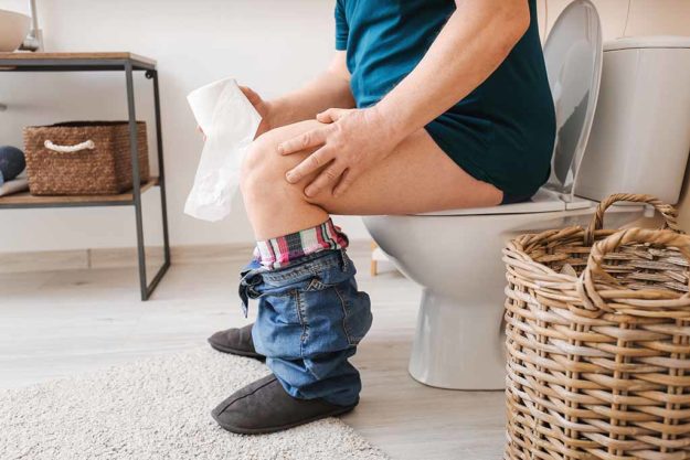 Elderly man with hemorrhoids sitting on toilet bowl in restroom Home Remedies For Relieving Constipation In The Elderly