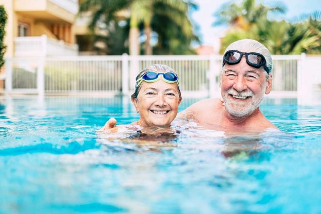 couple of cute seniors and pensioners in the water of the pool having fun and enjoying together