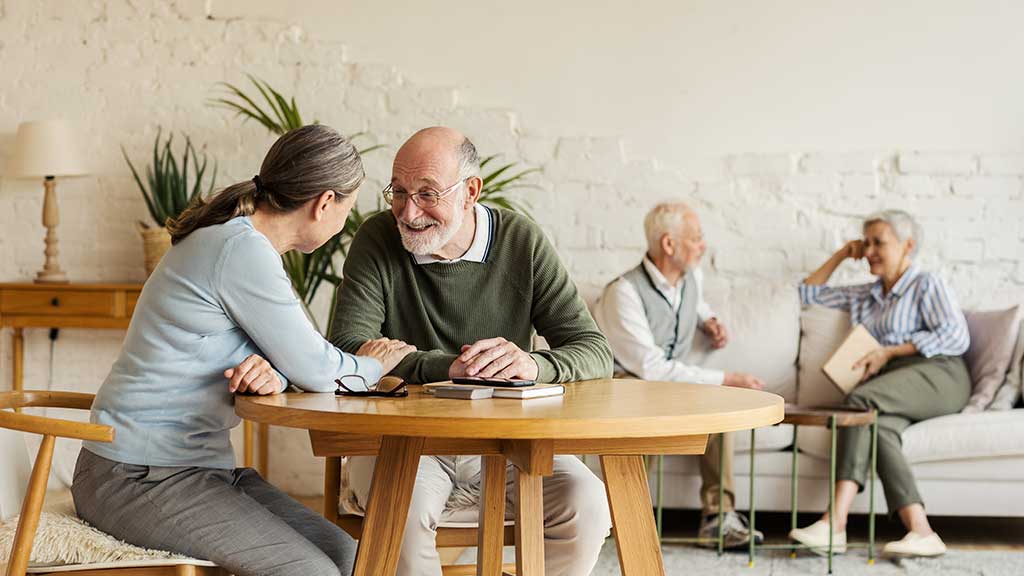 Elderly man and woman sitting at table and enjoying joyful talk