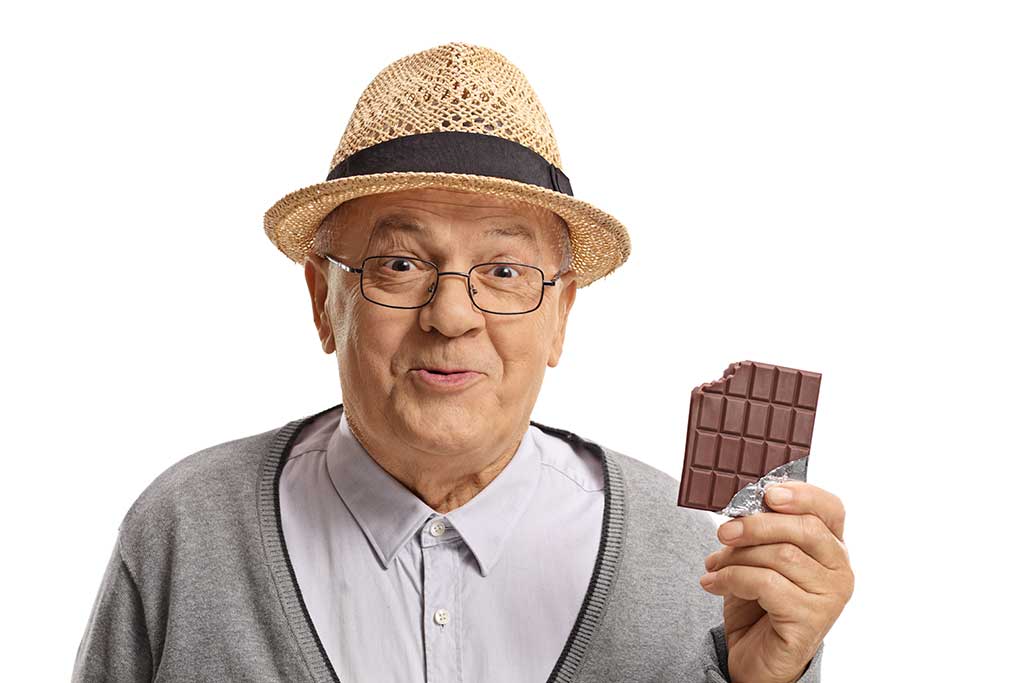 Happy mature man holding a bitten chocolate bar Happy mature man holding a bitten chocolate bar isolated on white background