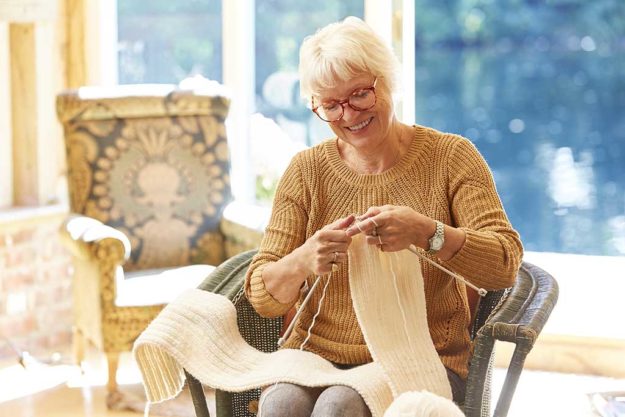 Senior woman knitting in living room
