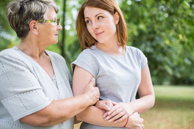 Grandmother is walking with her granddaughter in the park
