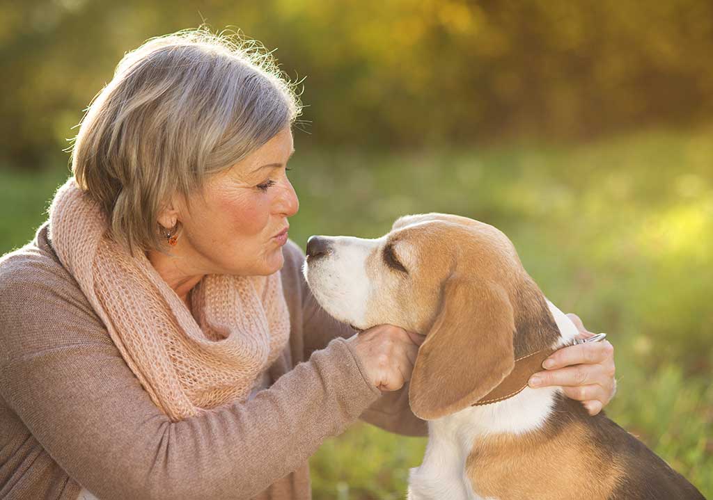 Active senior woman hugs dog