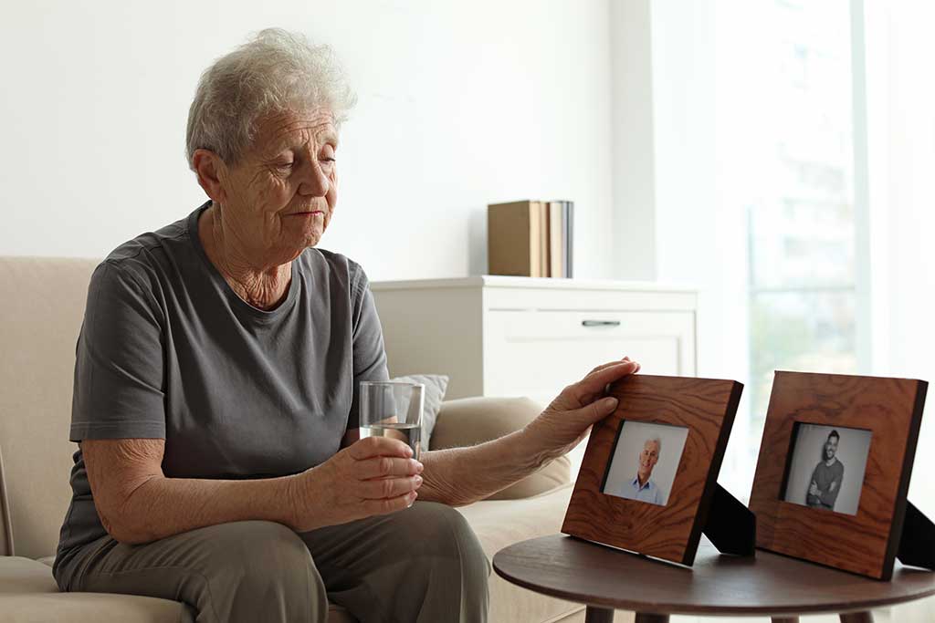Elderly woman with framed photos at home