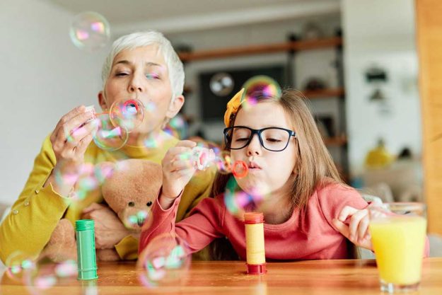 grandchild granddaughter grandma grandmother girl love family bl Portrait of Grandmother and granddaughter having fun blowing soap bubbles