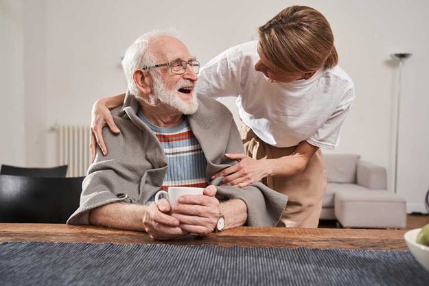 Nurse warming up with blanket her senior patient while working Nurse warming up with blanket her senior patient while working