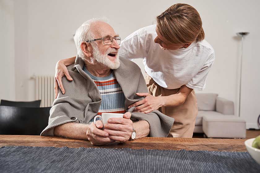 Nurse warming up with blanket her senior patient while working Nurse warming up with blanket her senior patient while working