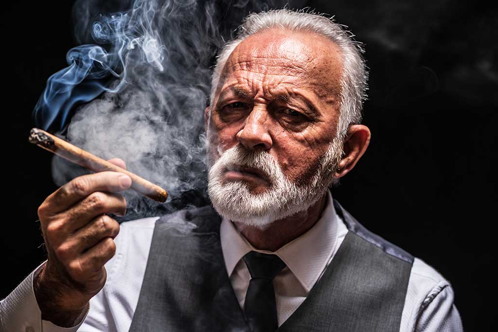 Portrait of serious senior man who is smoking cigar. Portrait of serious senior man who is smoking cigar