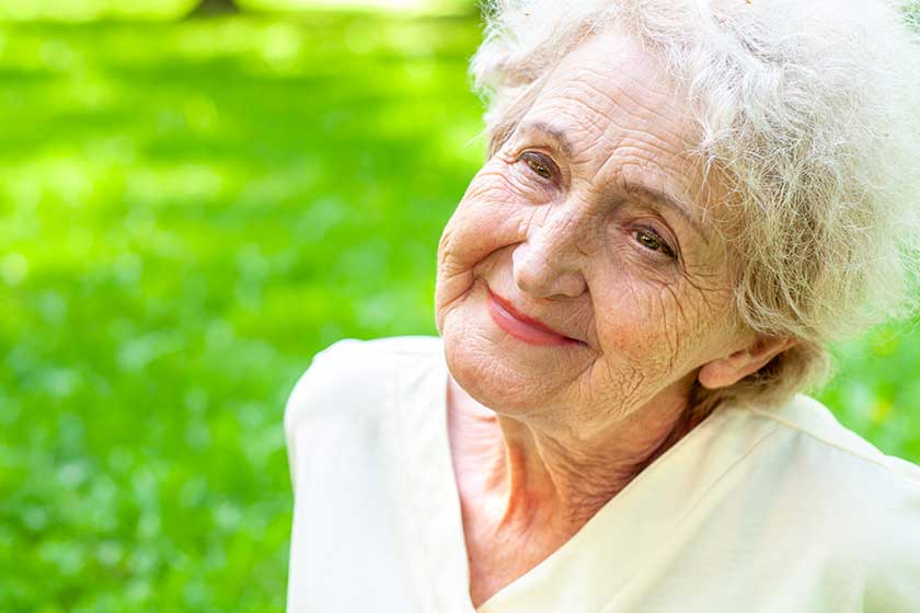 Pretty happy elderly woman on a background of spring greenery