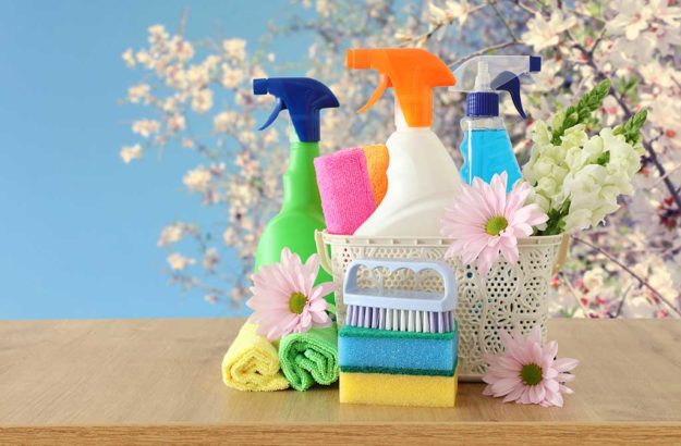 Spring cleaning concept with supplies on wooden table.