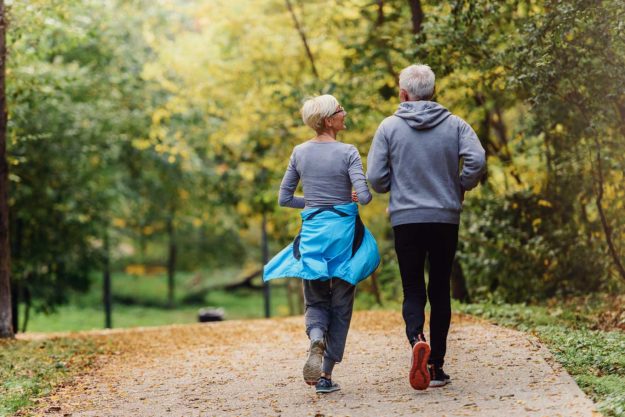 Cheerful active senior couple jogging in the park. Exercise toge Cheerful active senior couple jogging in the park. Exercise toge