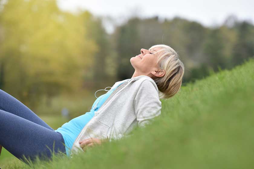Senior woman in fitness outfit relaxing in park