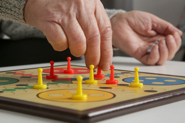 Senior woman playing board game with granddaughter or care giver.