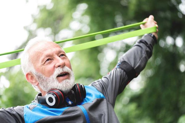 Senior sportsman exercising with resistance band at park Why Resistance Training Is Beneficial For You