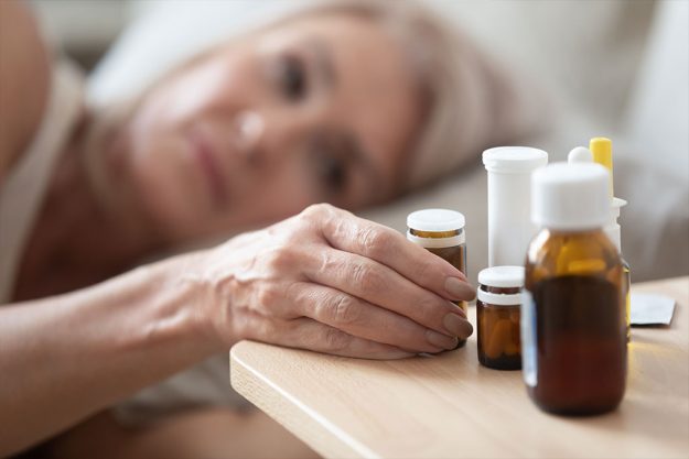 close-up-focus-on-wrinkled-female-hand-taking-glass-bottle