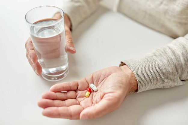 close up of old man hands with pills and water old man hands with pills and water