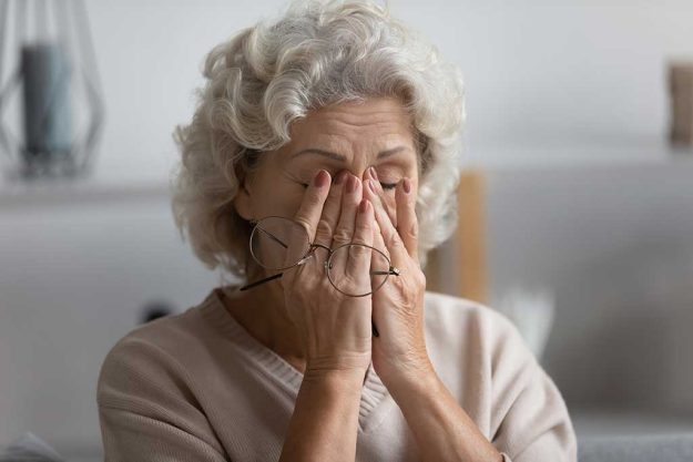 Exhausted elderly 60s woman take off glasses suffer from blurry vision or dizziness at home Exhausted elderly 60s woman take off glasses suffer from blurry vision or dizziness at home