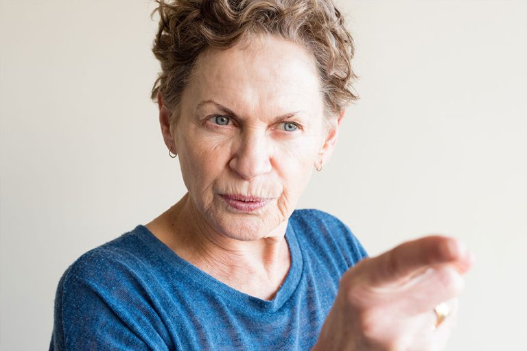 Angry older woman in blue top pointing finger
