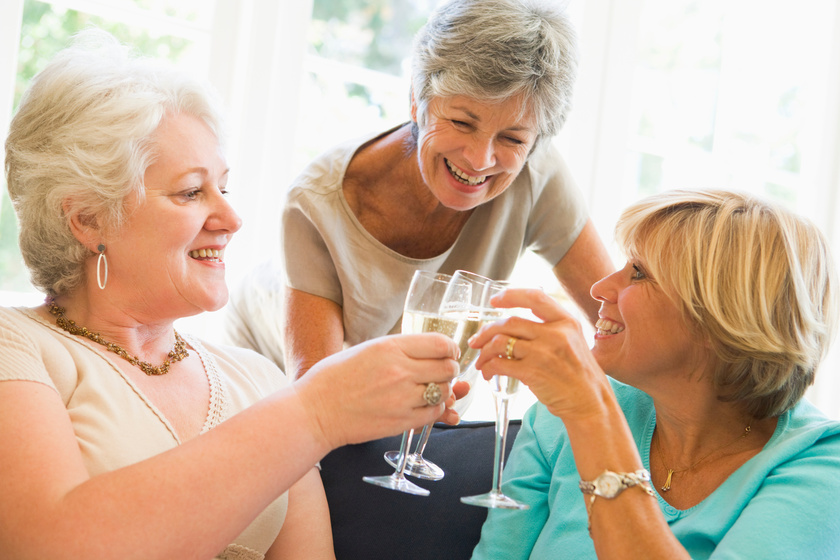Three women in living room toasting champagne and smiling