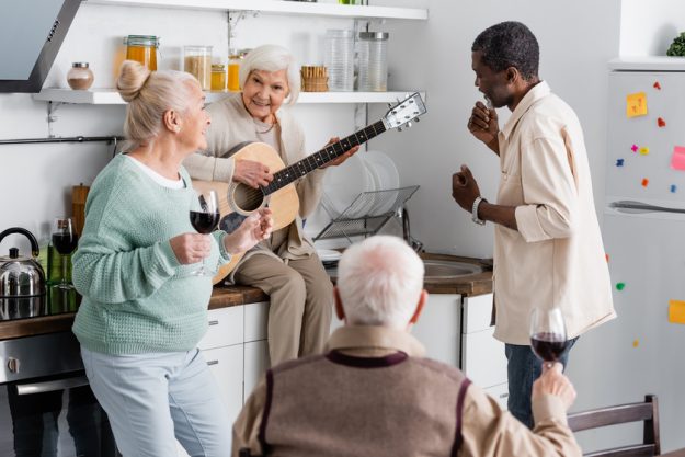 happy senior woman playing acoustic guitar near retired multicul