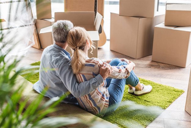 back view of elderly couple embracing while sitting on carpet back view of elderly couple embracing while sitting on carpet