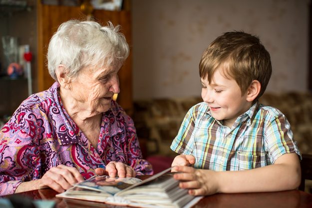 Grandma shows photo album to little grandson. Grandma shows photo album to little grandson.