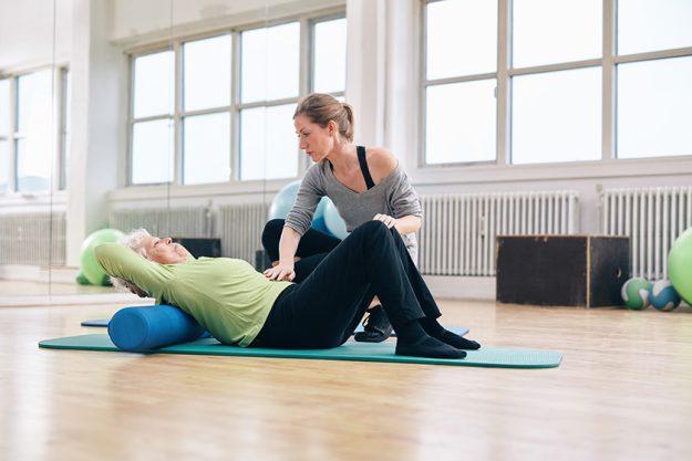 Physical therapist helping elder woman at gym