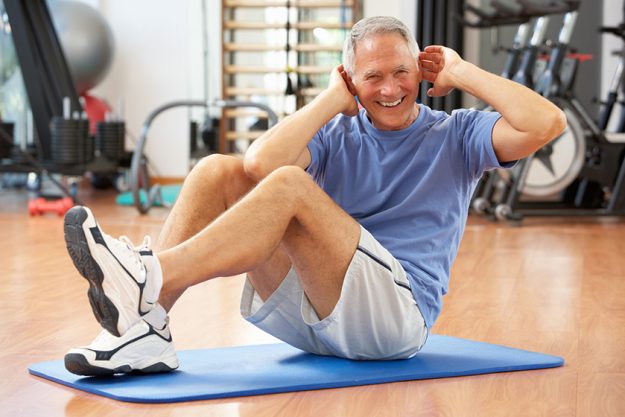 Senior Man Doing Sit Ups In Gym