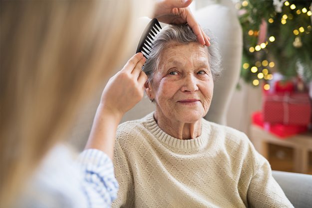 a-health-visitA health visitor combing hair of senior woman at home at Christmas timeor-combing-hair-of-senior-woman-at-home-at-christmas-time A health visitor combing hair of senior woman at home at Christmas time