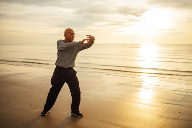 Asian Senior old man practice Tai chi and Yoga pose on the beach sunrise Asian Senior old man practice Tai chi and Yoga pose on the beach sunrise