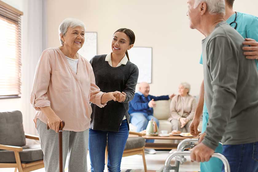 Care workers helping to elderly patients to walk in geriatric hospice Care workers helping to elderly patients to walk in geriatric hospice