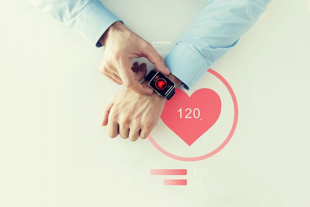 close up of hands with heart icon on smart watch
