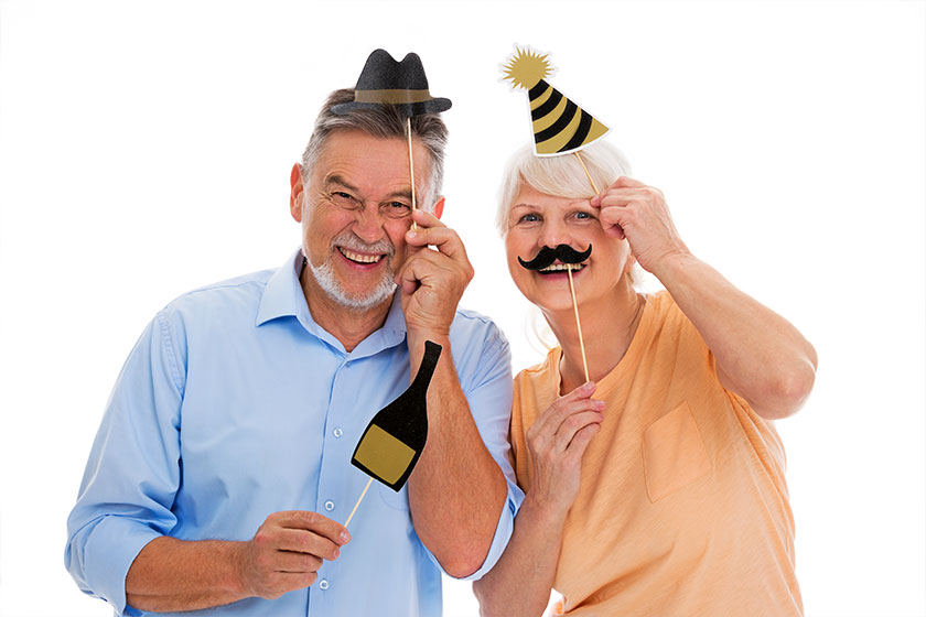 Funny senior couple holding party hats and mustaches on sticks Funny senior couple holding party hats and mustaches on sticks