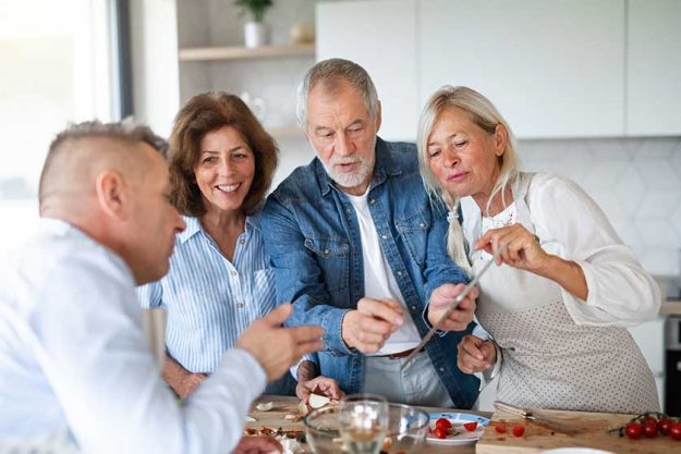 Group of senior friends at dinner party at home, cooking Group of senior friends at dinner party at home, cooking