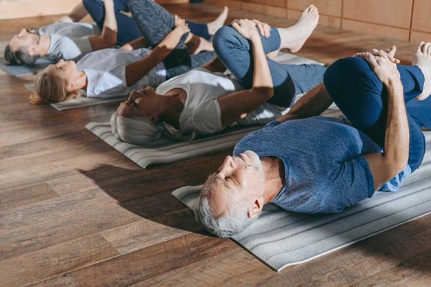 group of senior people stretching in yoga mats in studio group of senior people stretching in yoga mats in studio