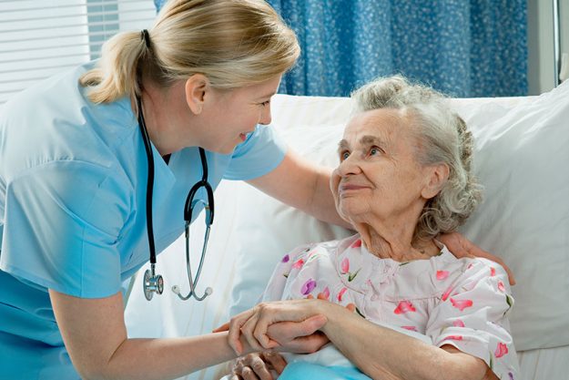 Nurse cares for a elderly woman lying in bed