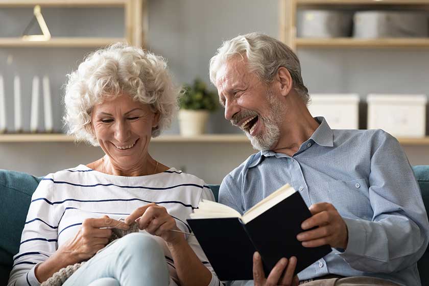 Overjoyed elderly mature couple spouses sit rest on couch in living room Overjoyed elderly mature couple spouses sit rest on couch in living room