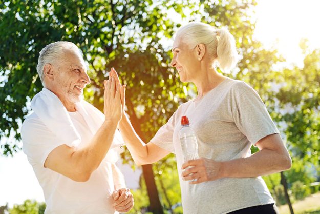 Positive aged couple resting in the park after jogging Positive aged couple resting in the park after jogging