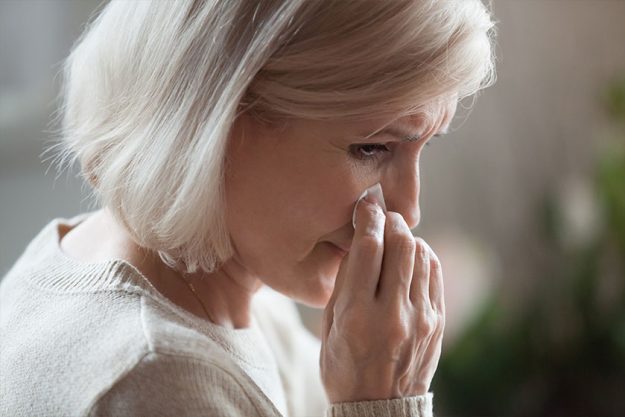 Sad senior middle aged woman widow mourning crying wiping tears