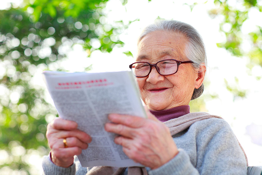 Senior asian woman reading book in the yard