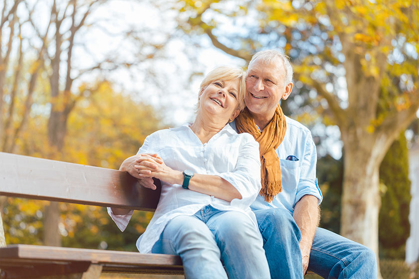 Senioren Paar sitzt im Herbst auf Parkbank Senioren Paar sitzt im Herbst auf Parkbank