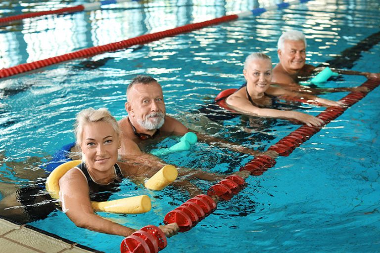 Sportive senior people doing exercises in indoor swimming pool
