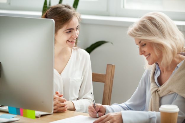 Senior female client signing contract with smiling manager in of Senior female client signing contract with smiling manager in of